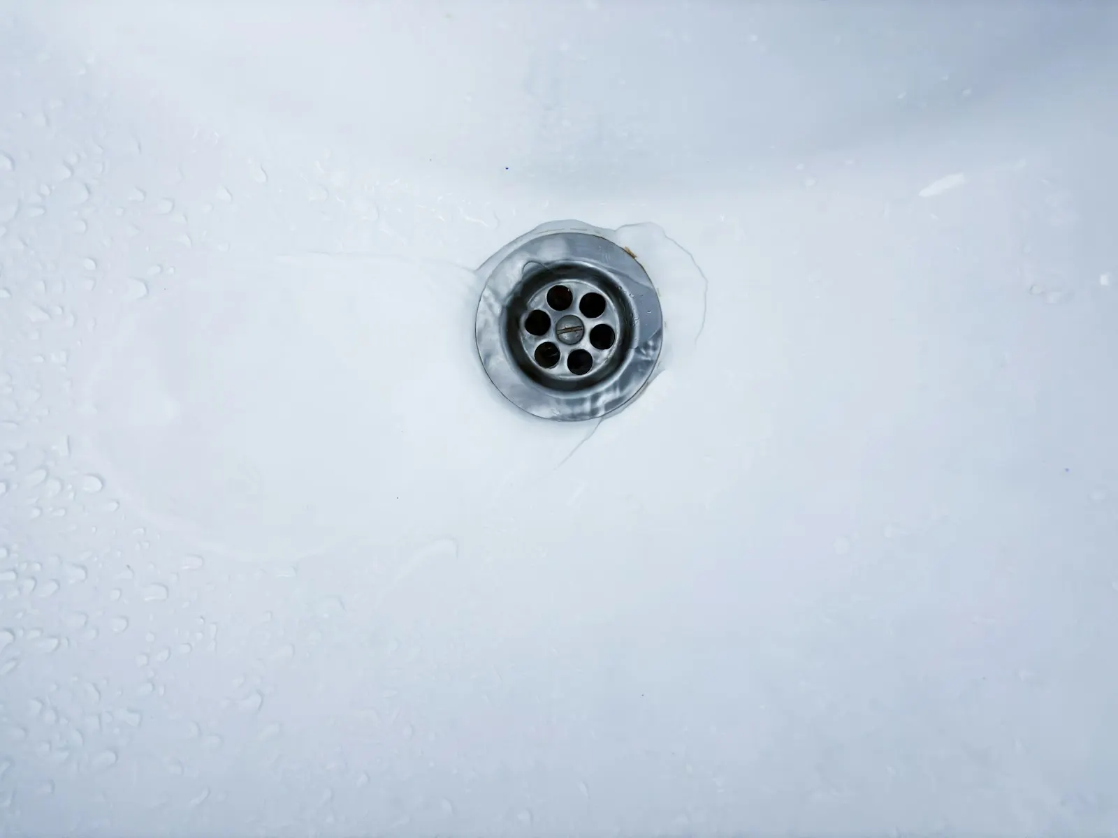 Water running down a white sink drain