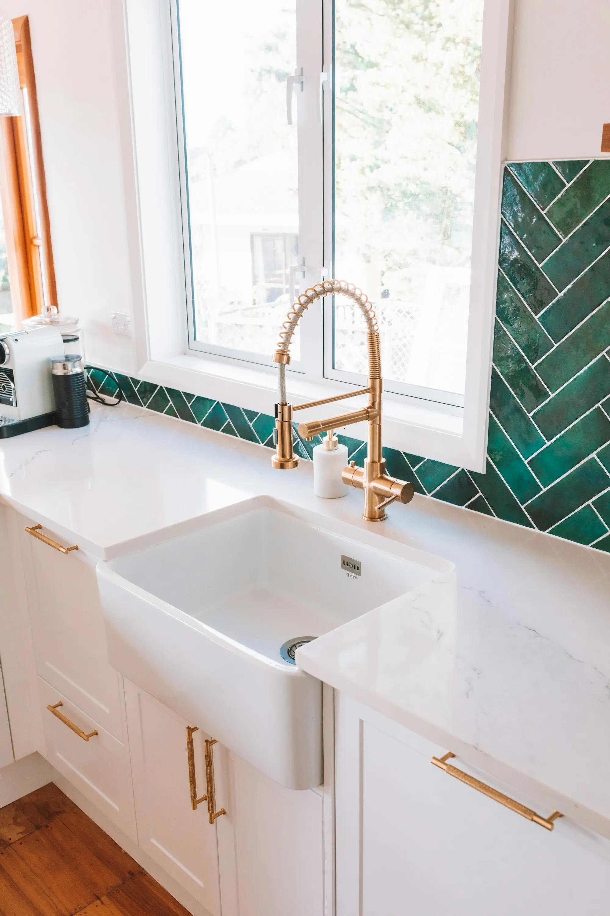 A bright kitchen sink with a brass faucet under the window
