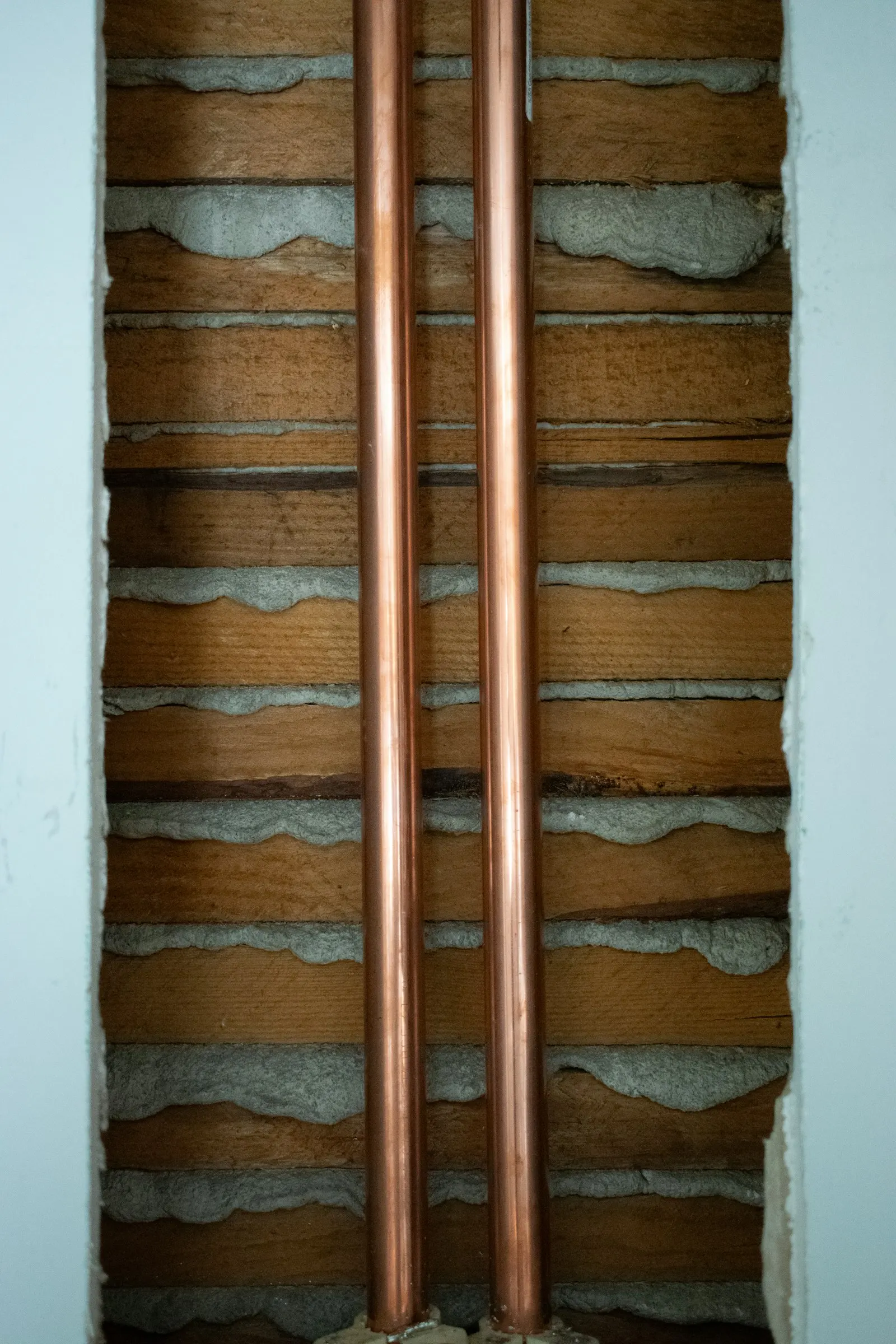 Two new copper pipes running up an open wall