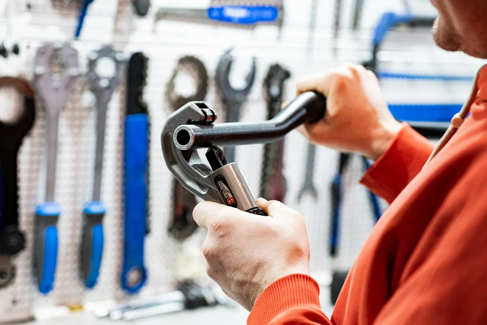 A plumber choosing a wrench from a wall of tools